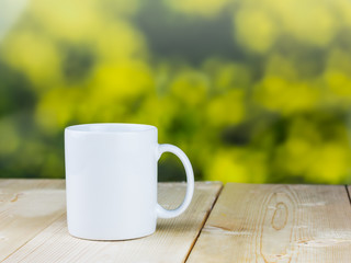White coffee cup on wood table with blurred green background