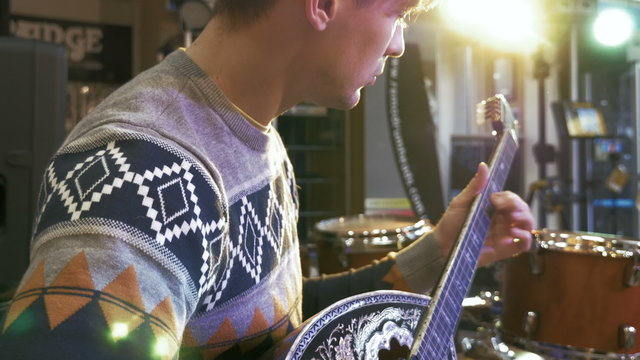 Young man playing on turkish saz guitar in the lights, 4k