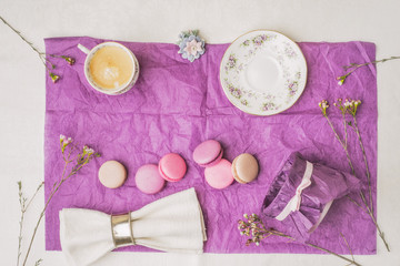 Cup of coffee with macaroons and decoration on the purple paper