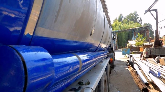 Tank semi trailer with a blue stripe is on the repair