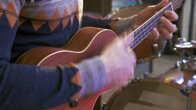 	Young man playing on ukulele guitar, 4k