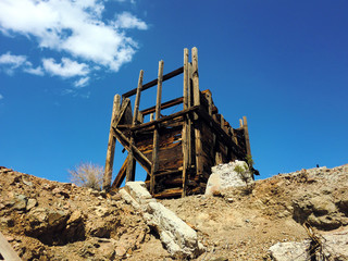 Abandoned old silver mine wooden structure in sun - landscape color photo