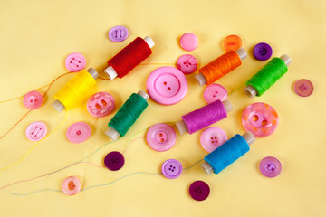 Sewing thread and buttons on yellow cloth