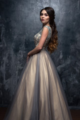 Fashion beauty portrait of gorgeous young woman with long curly hair in luxury evening dress