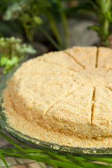 napoleon cake of puff cakes and custard, sprinkled with crumbs, divided into portions, on a glass stand