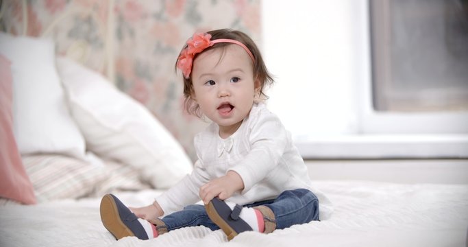 portrait of little Asian baby girl having fun playing in the room, smiling and laughing, slow motion.