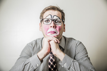 young businessman in the make-up clown, wrapt in thought