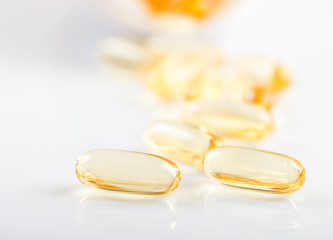 shiny yellow vitamin e fish oil capsule spilling out of pill bot