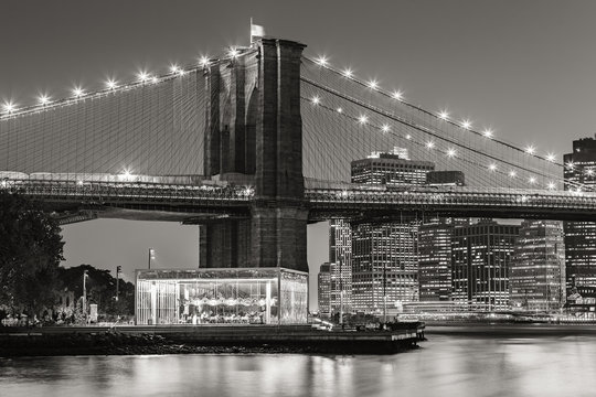 Fototapeta Black and White of  Brooklyn Bridge Tower at twilight with carousel and skyscrapers of Lower Manhattan. Financial District. New York City