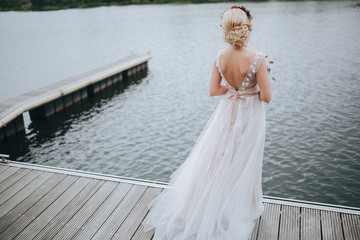 Fototapeta na wymiar Wedding. The bride's bouquet. Wedding bouquet . The bride in a white dress standing on a pier at the lake and holding a bouquet of red and pink flowers with berries and greens with a marsala ribbon