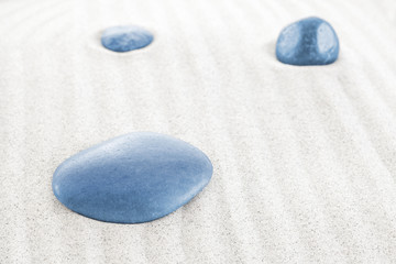 Fototapeta na wymiar Three blue stones on white sand.