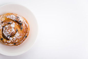 top view of sweet roll bun with raisins over white