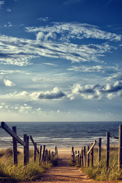 Weg zum Strand am Meer mit blauem Himmel und Wolken