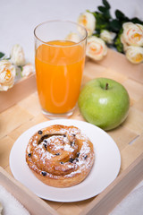 breakfast with bun, apple and juice on wooden tray