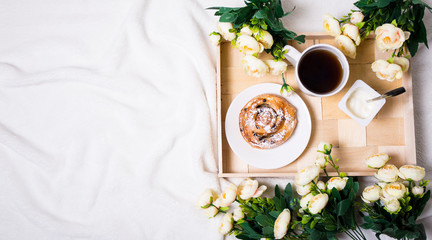 top view of breakfast with bun, tea and yoghurt on wooden tray a