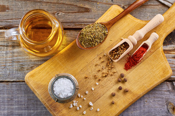 Various spices, salt, coriander seeds, chilly, herbs, allspice, olive oil, on wooden board.