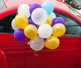 Fotobehang разноцветные шарики воздушные с гелием  привязанные к красной машине © leilik