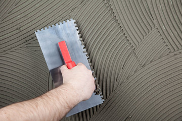the worker applies glue for a tile on a wall