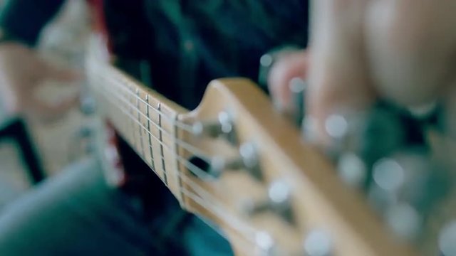 Close up shot of young Caucasian male adjusting an electric guitar. 4k 60 FPS Slow motion. Shot with Blackmagic URSA Mini