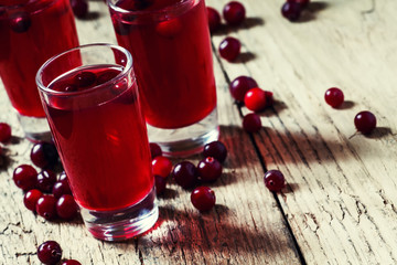 Red cocktail with natural cranberry juice and vodka, old wooden