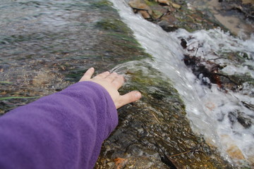 Mano de chica tocando el agua de la riera de Santa Coloma de Farners