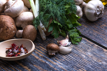 Mushrooms, parsley, dill, onion, olive oil, spices - ingredients for the preparation of mushroom dishes on the wooden background
