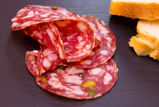 Slices of salami with pistachios on top in slate
