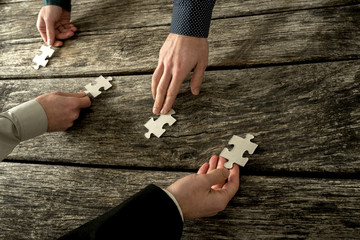 Hands of four businessman placing each a piece of puzzle in a ro