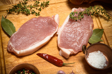 Fresh meat steaks on light wooden cutting board. Toned