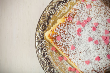 Homemade cake on a metal plate on colored wooden background. Ton