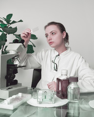 Young female microscopist selects a tissue sample