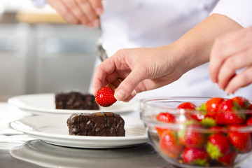 Chefs decorates dessert cake with chocolate sauce in kitchen