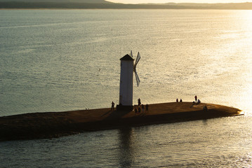 Mill shape lantern on breakwater till sundown