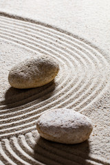 Fototapeta na wymiar zen sand still-life - textured stones set on sinuous waves for concept of change or suppleness with inner peace, closeup