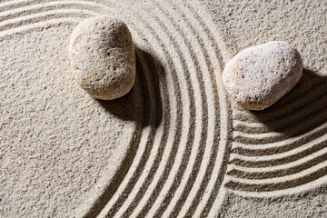 Fototapeta na wymiar zen sand still-life - two stones across lines to give different directions for concept of change or flexibility with peace, top view