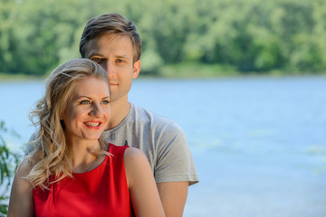 Young happy couple hugging and laughing on river background