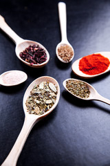 spice in wood spoon on a black background. food