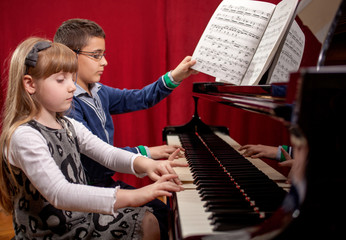 young pianists,boy and girl playing a grand piano