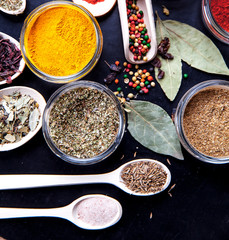 Spices on black background in special jars. Food