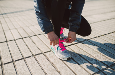 Female jogger tying her running shoes preparing for a jog