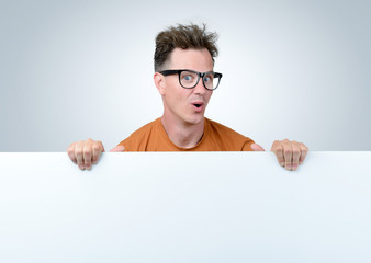 Positive man with glasses holding white billboard