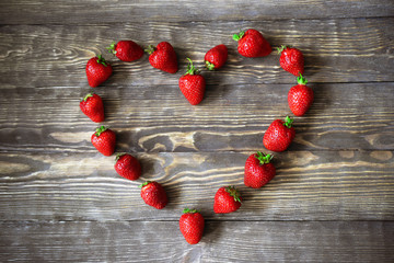 juicy strawberries in a heart shape on the old wooden background