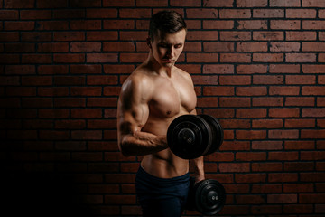 Fototapeta na wymiar Young sports guy trains the biceps in the gym
