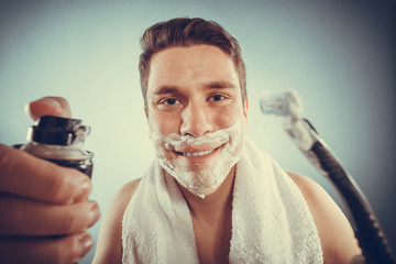 Handsome man with shaving cream foam can and razor