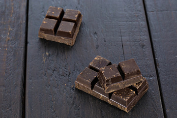 Dark chocolate pieces on wooden table background