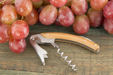 opener wine and grapes on wooden background.