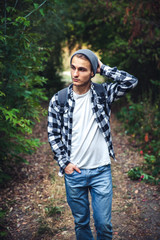 Portrait of young handsome man with backpack wanderer walk in the woods