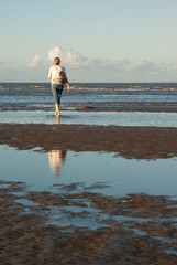 Woman walking alone on beach in late afternoon
