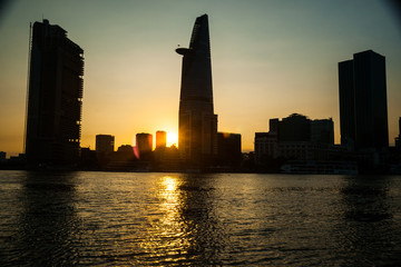 Panorama of Ho Chi Minh viewed over Saigon river. Breathtaking dramatic light of sunset is highlighted by lens flare effect created by vintage photo equipment.