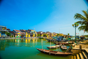 Fototapeta na wymiar Traditional boats in front of ancient architecture in Hoi An, Vietnam. Hoi An is the World's Cultural heritage site, famous for mixed cultures & architecture.